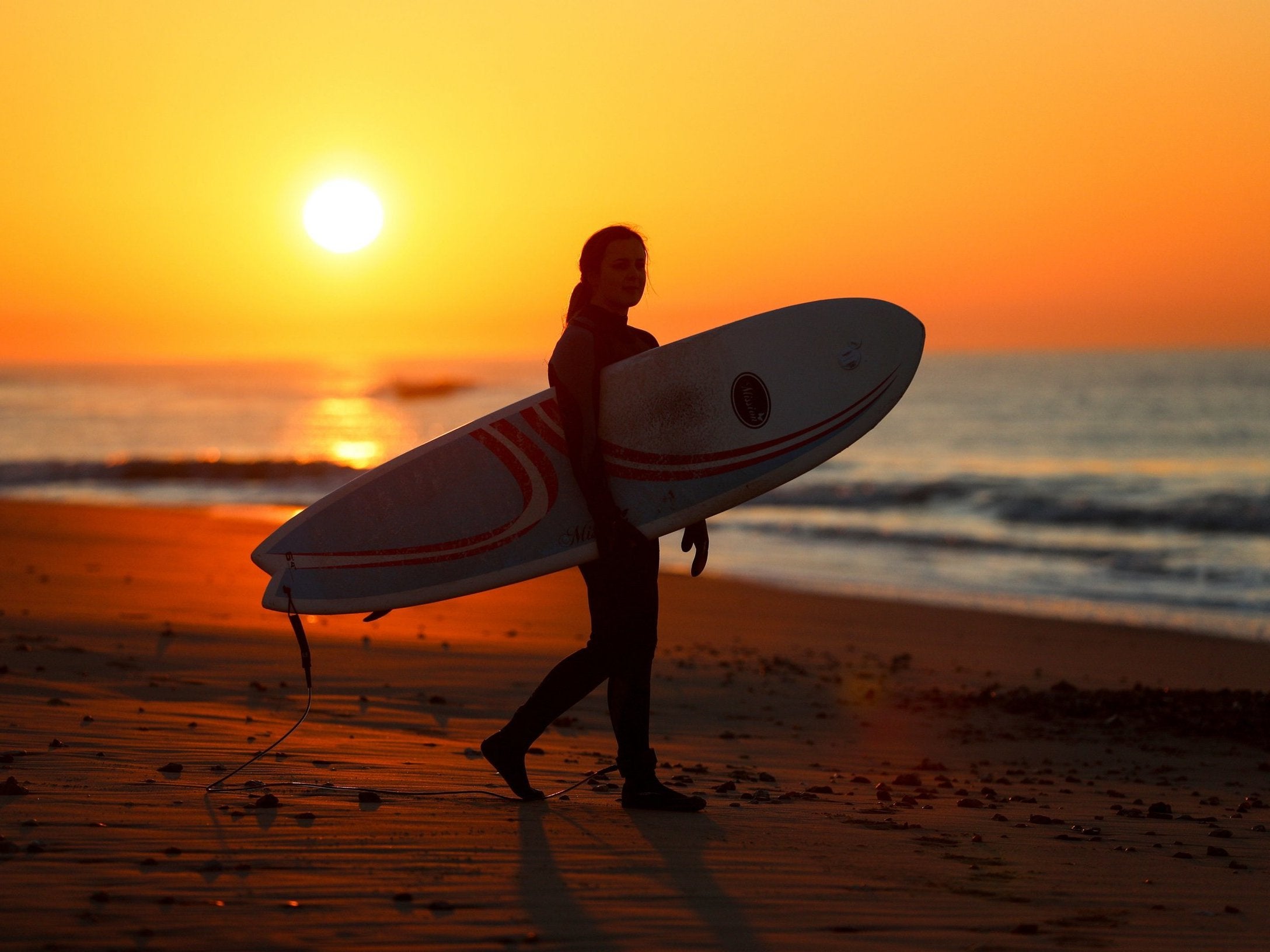A surfer makes their way to the sea during sunrise at Boscombe beach in Dorset as Britain could experience more record-breaking temperatures this week after Monday became the warmest winter day on record