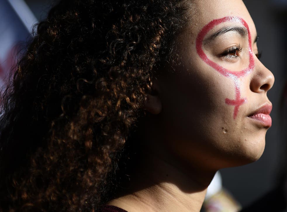 A woman with the female gender pictogram made up on her face attends a demonstration as part of the 40th International Women's Day on 8 March 2017 in Marseille