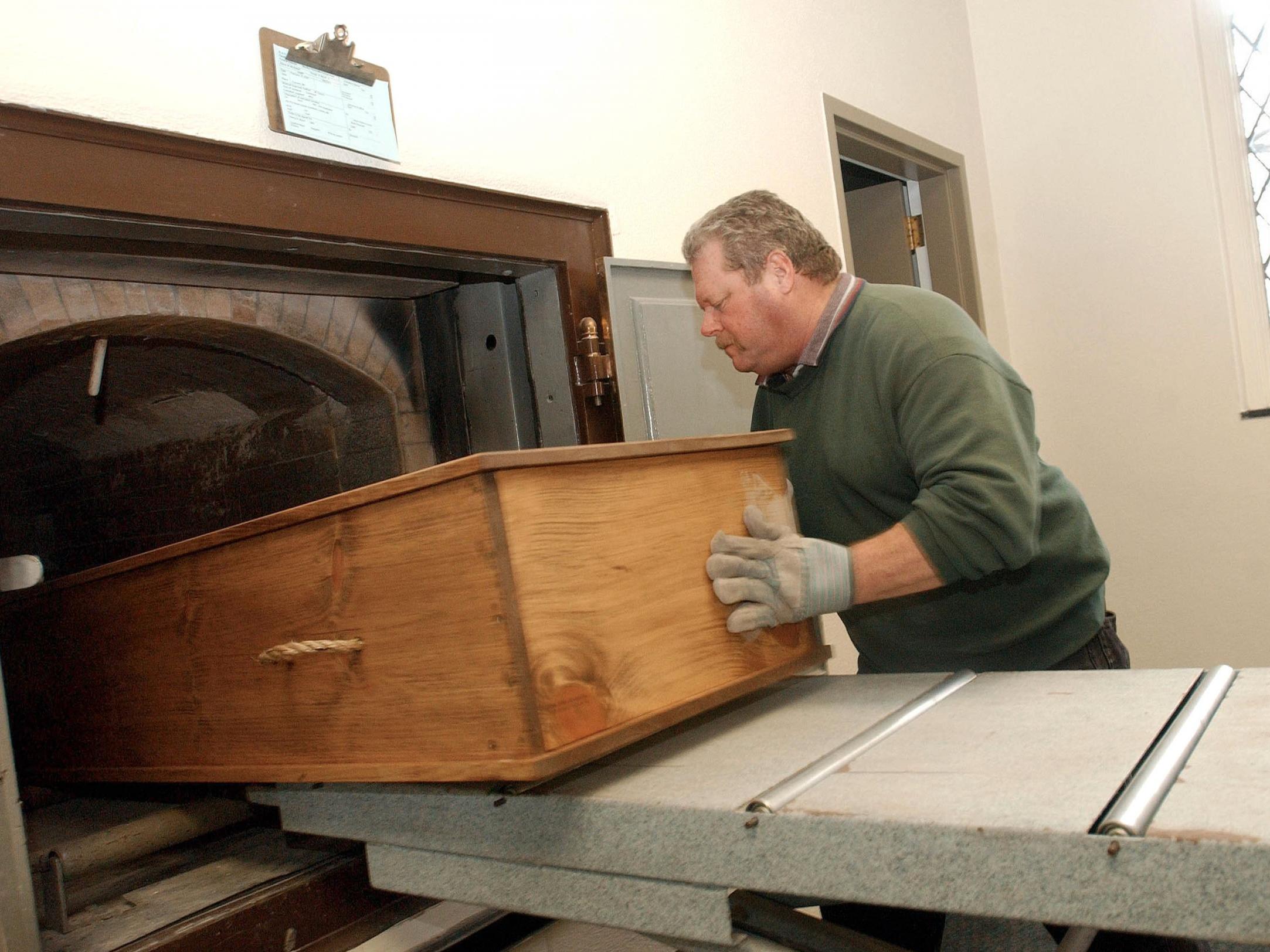 Crematory operator places a coffin into the retort, or cremation ovens, at Mount Auburn Cemetary in Watertown, MA.