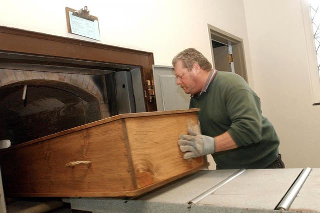 Crematory operator places a coffin into the retort, or cremation ovens, at Mount Auburn Cemetary in Watertown, MA.
