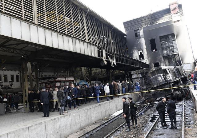 Firefighters and onlookers gather at the scene of a fiery train crash at the Egyptian capital Cairo's main railway station