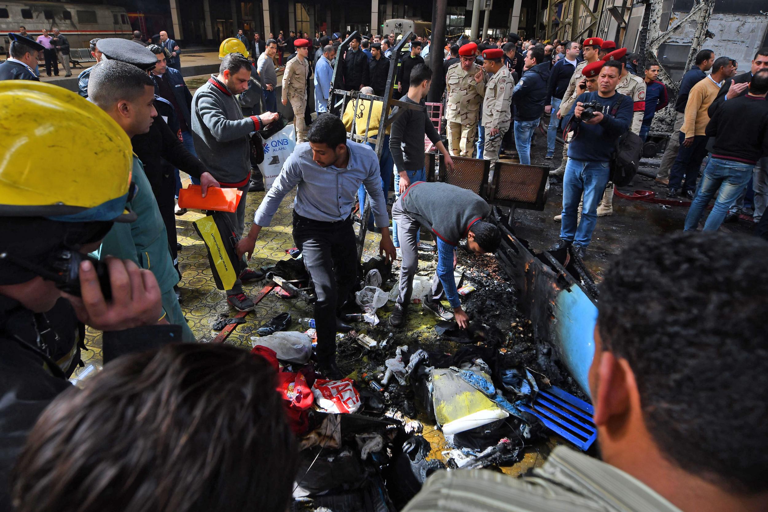 Members of the security forces and onlookers gather at the scene of a fiery train crash at the Egyptian capital Cairo's main railway station