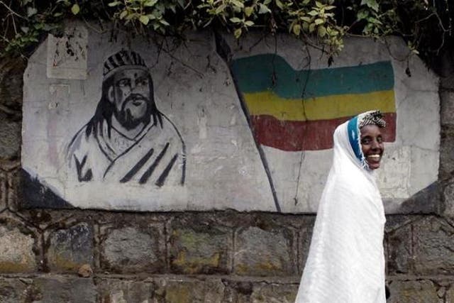 An Ethiopian woman walks past a mural depicting Ethiopia's Emperor Tewodros II in Addis Ababa, Ethiopia.
