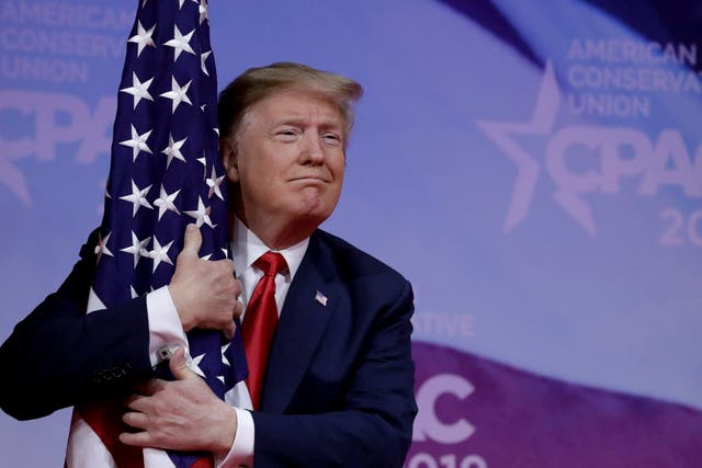 U.S. President Donald Trump hugs American flag at the Conservative Political Action Conference (CPAC) annual meeting at National Harbor near Washington, U.S., March 2, 2019.