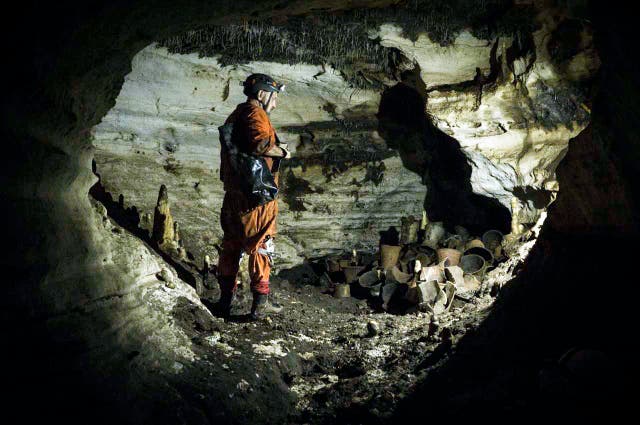 <p>An archaeologist stands next to pre-columbian artifacts in a cave at the Mayan ruins of Chichen Itza</p>