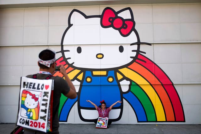 Hello Kitty fans take pictures outside a mural at a convention in Los Angeles
