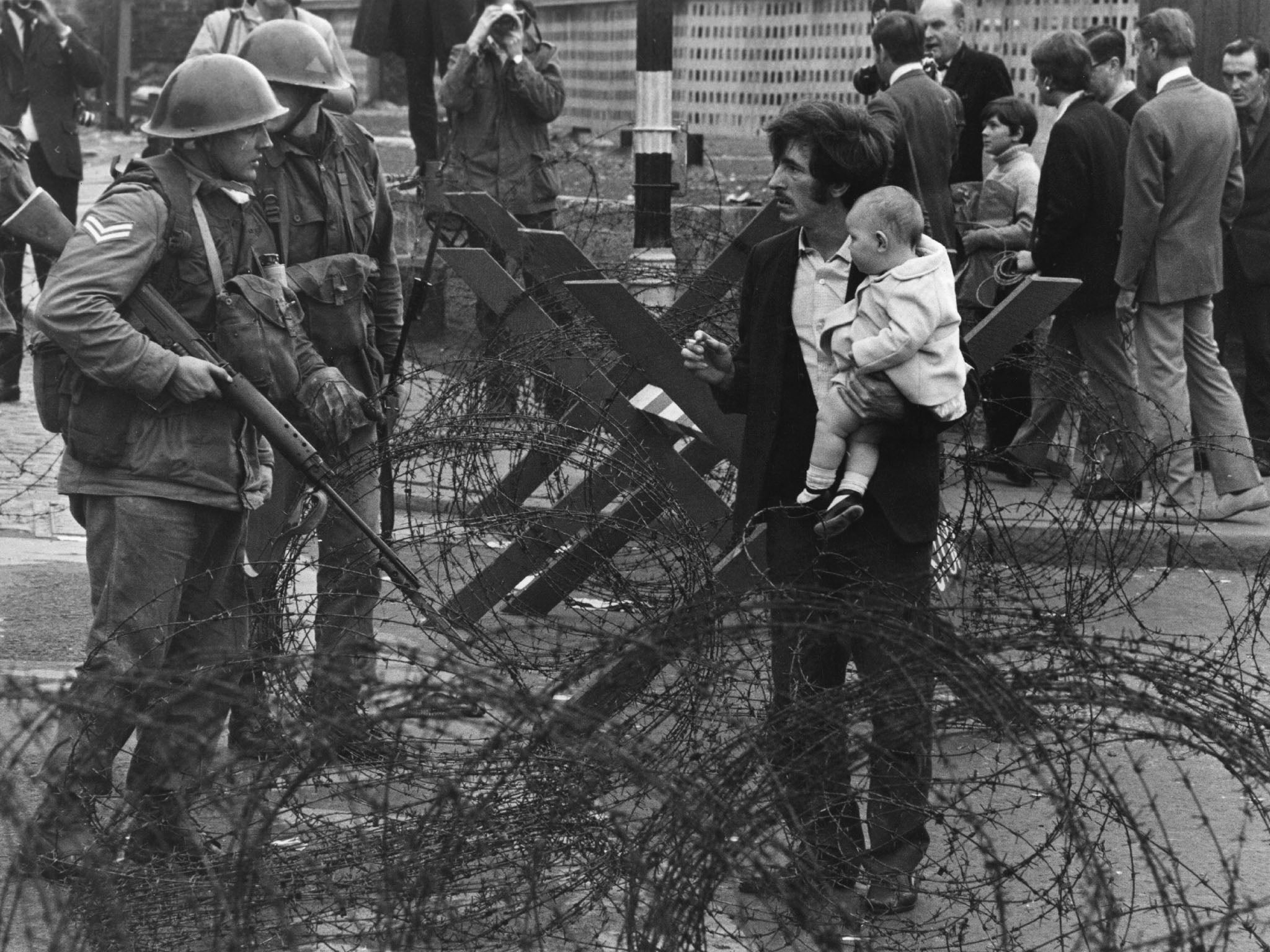 British soldiers stop a man trying to carry his baby through a barricade on the Catholic Falls Road area of Belfast in August 1969