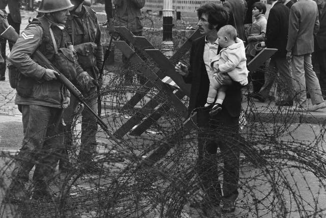 British soldiers stop a man trying to carry his baby through a  barricade on the Catholic Falls Road area of Belfast in August 1969