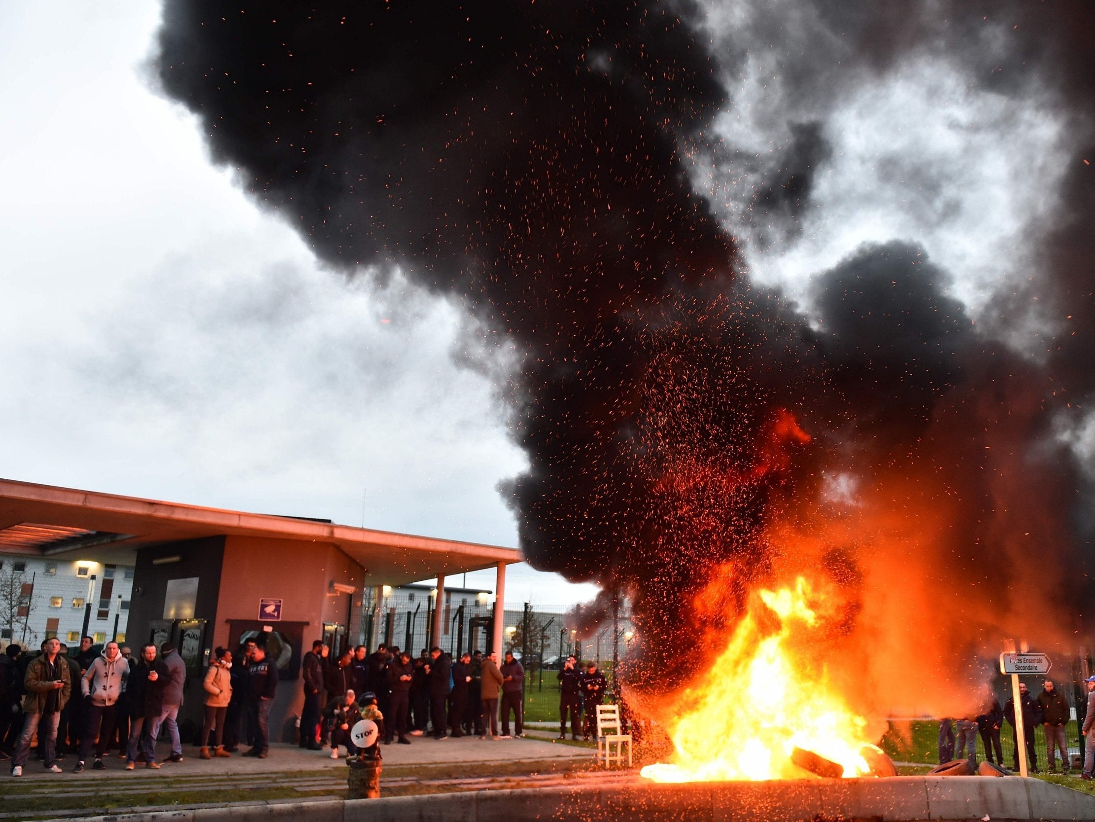 Waste burns as guards block the entrance to the penitentiary centre of Alencon, in Conde-sur-Sarthe