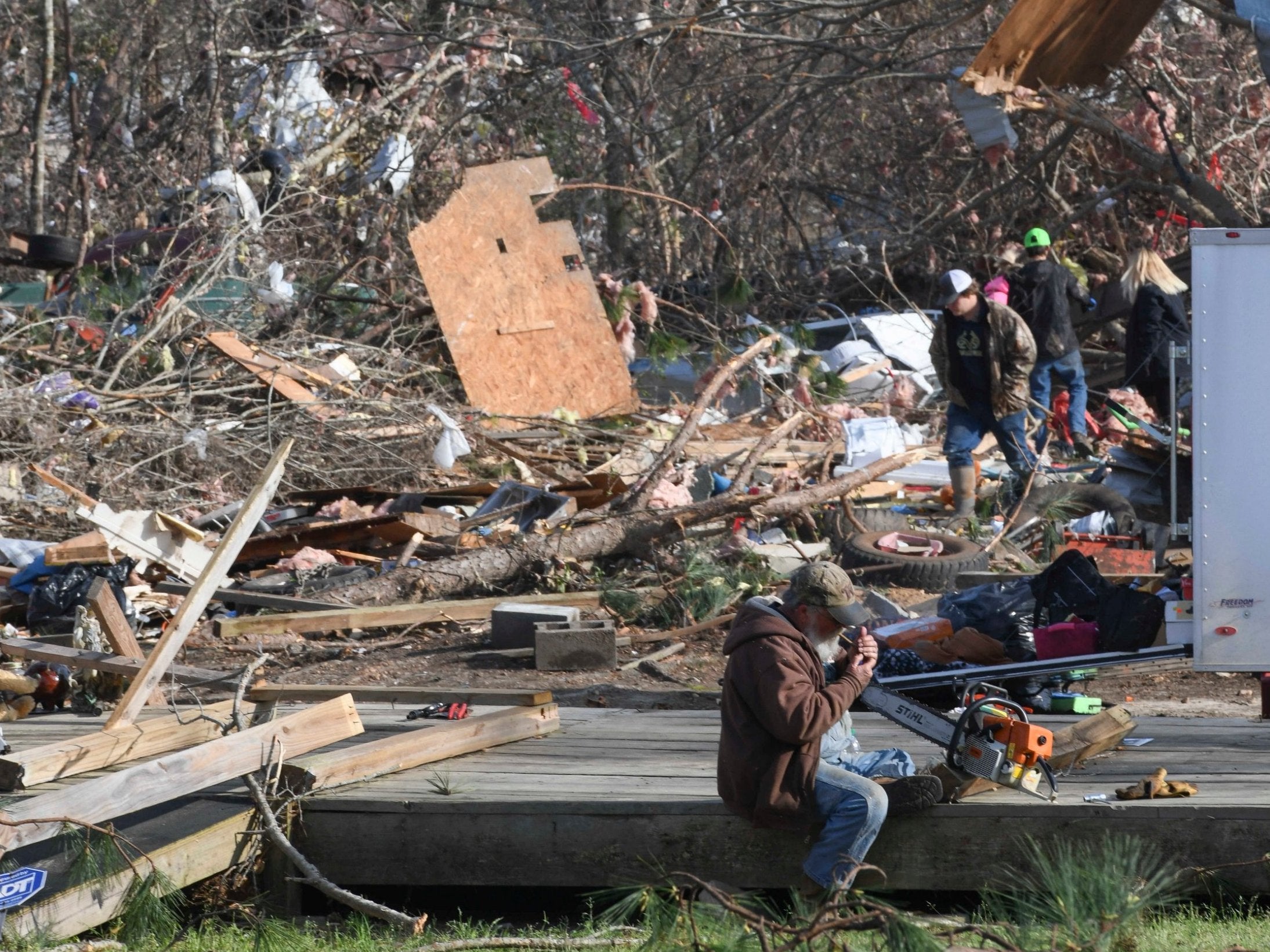 Residents and their families work to clear tornado damage in Alabama