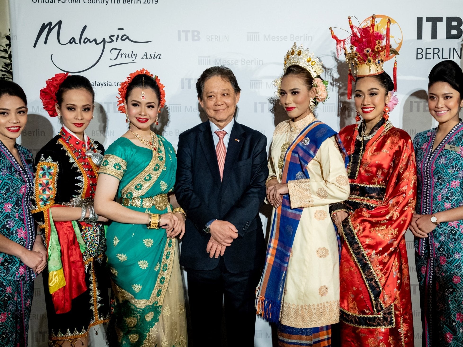 Malaysian minister of tourism, art and culture, Mohammadin Ketapi, poses with women wearing traditional Malaysian costumes for a photo prior to the International Travel Trade Show (ITB) in Berlin