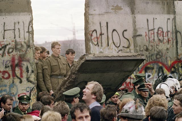 The day the wall came down: East German guards watch on as the concrete division comes tumbling down