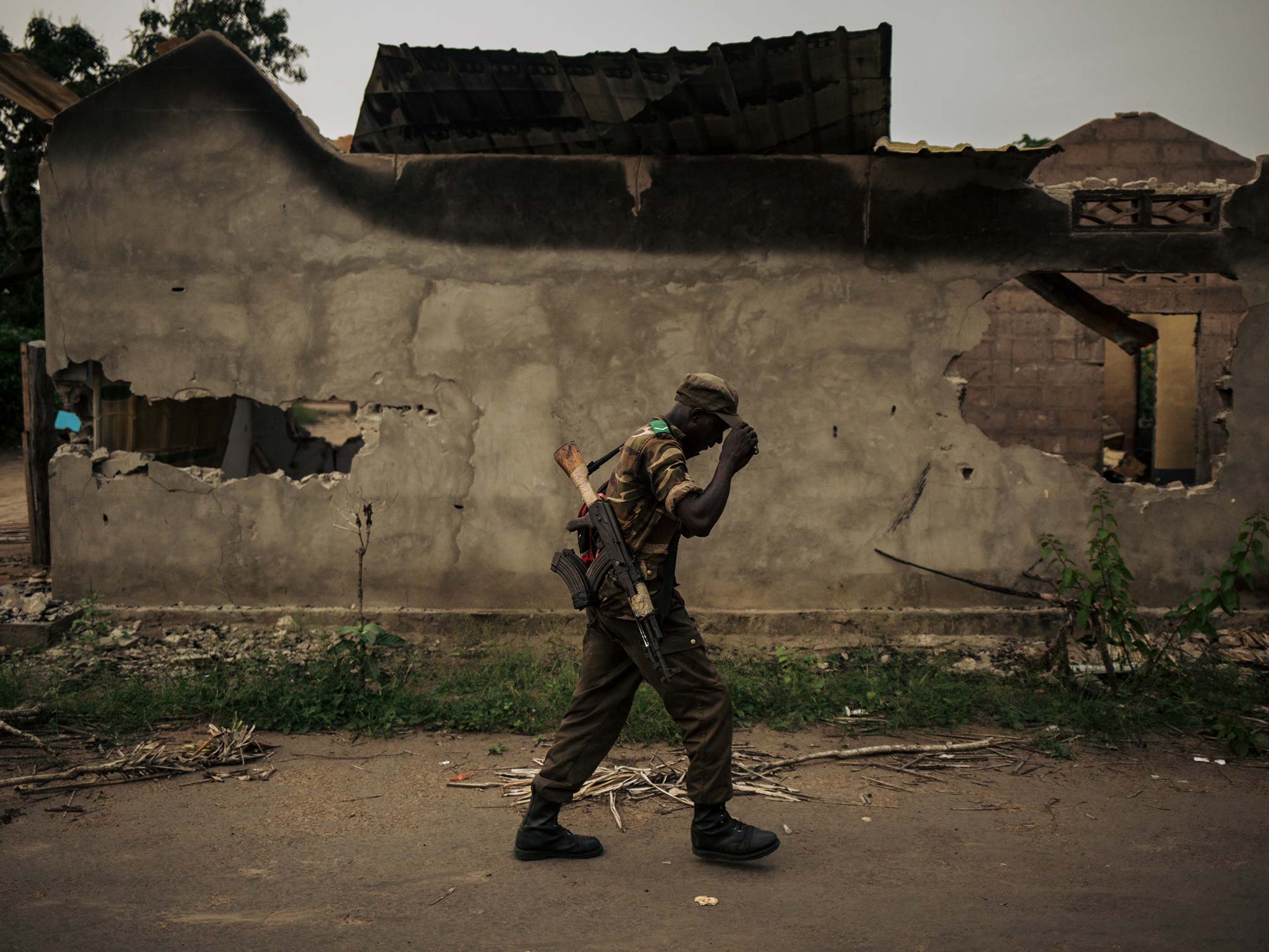 A member of the Congolese armed forces walks past a burnt building in Yumbi in February