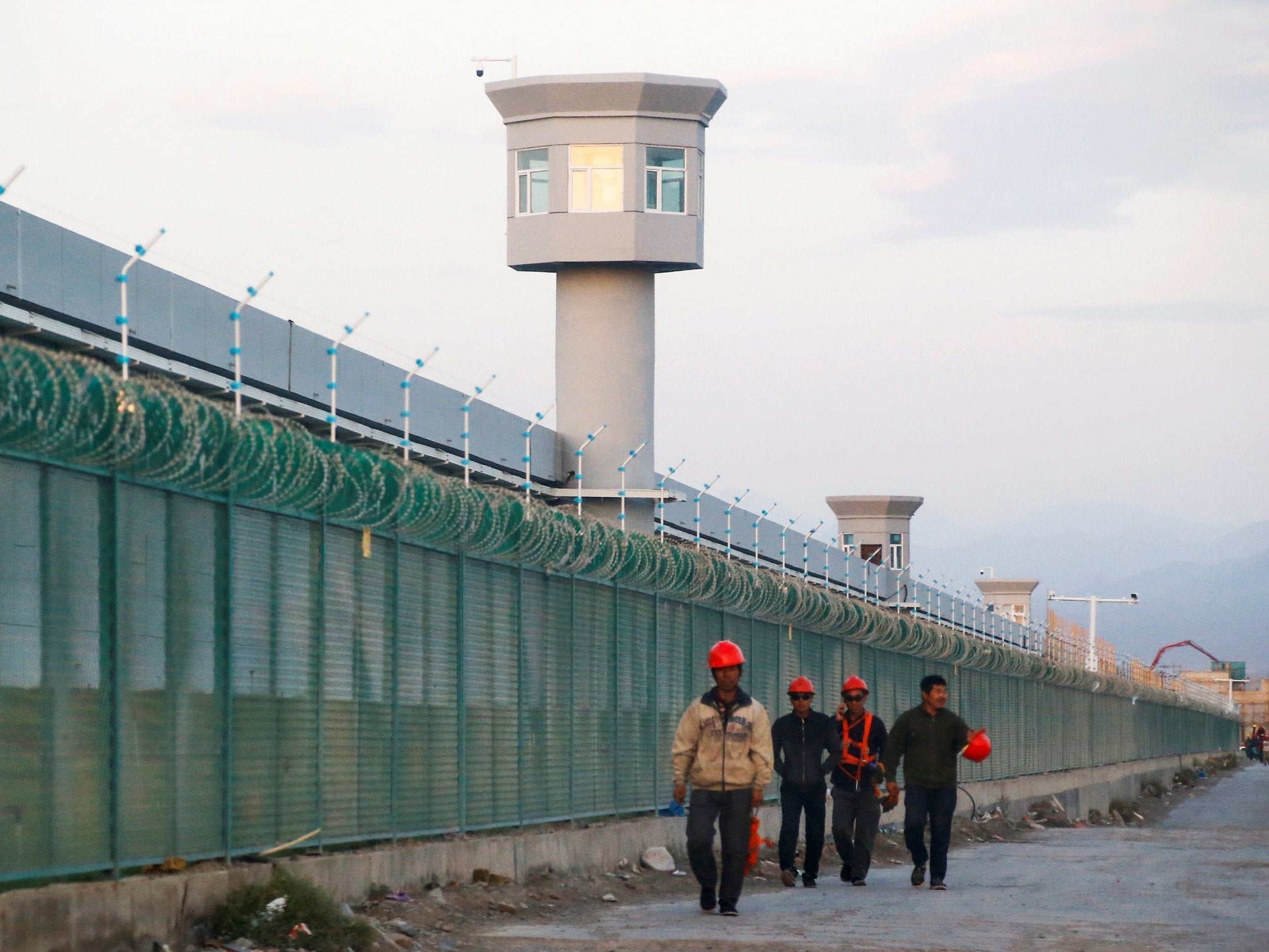 Workers walk beside the fence of an internment camp in Xinjiang, China, on 4 September, 2018.