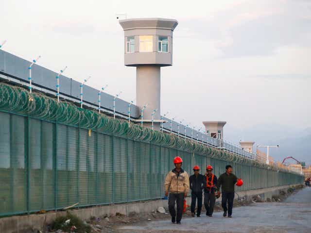 <p>Workers walk beside the fence of an internment camp in Xinjiang, China, on 4 September, 2018. </p>