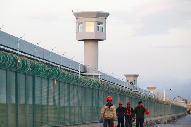 <p>Workers walk beside the fence of an internment camp in Xinjiang, China, on 4 September, 2018. </p>