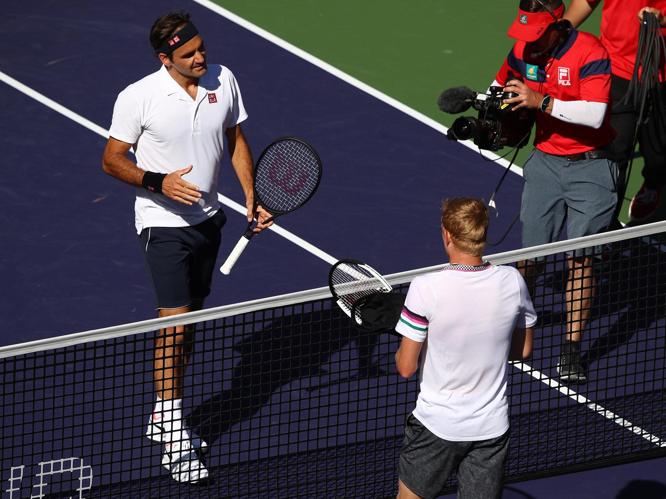 Roger Federer shakes hands at the net after his straight sets victory against Kyle Edmund