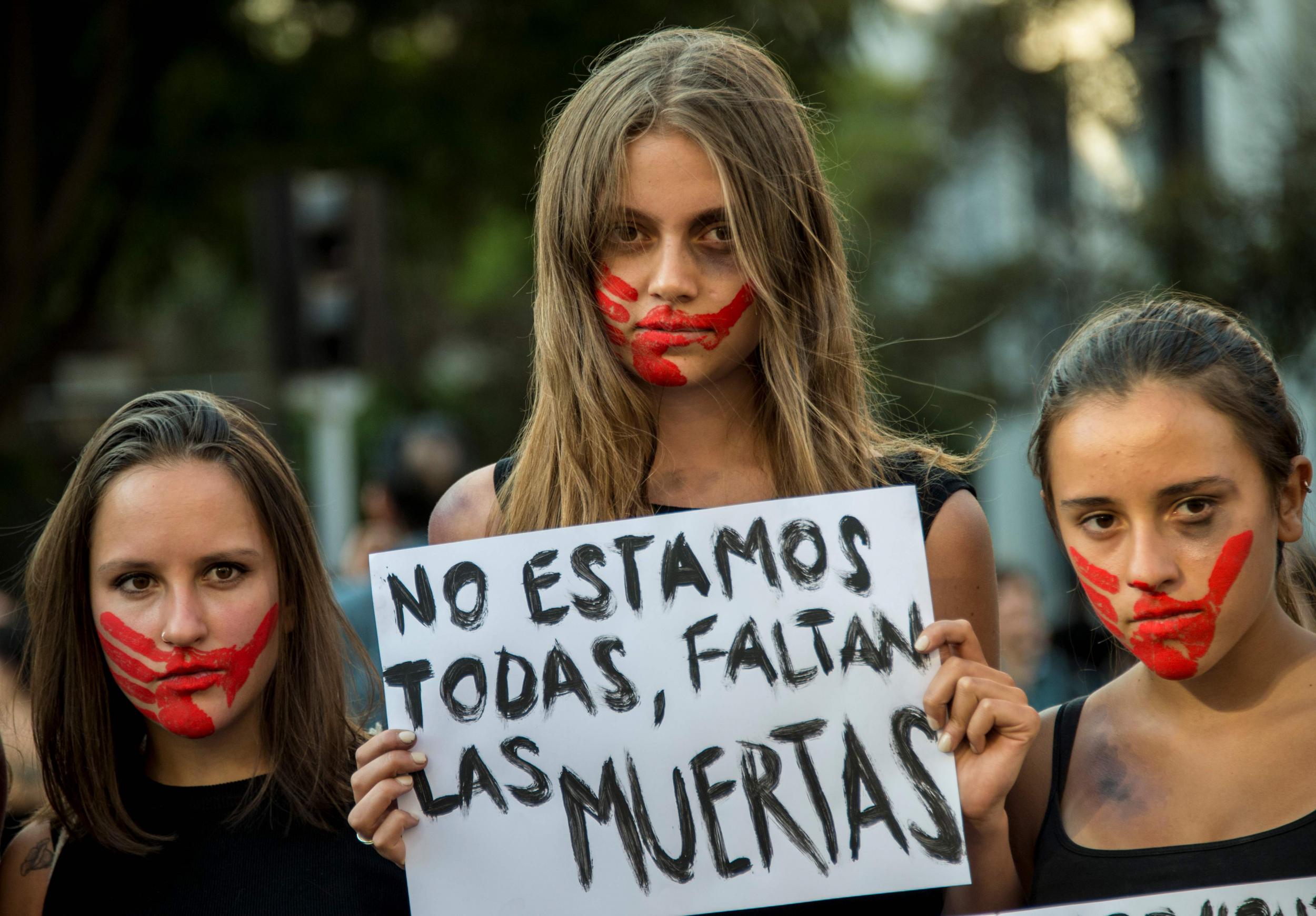 A young woman holds a placard reading “We are not all of us, the dead ones are missing” while taking part in a march on International Women’s Day in Santiago last week