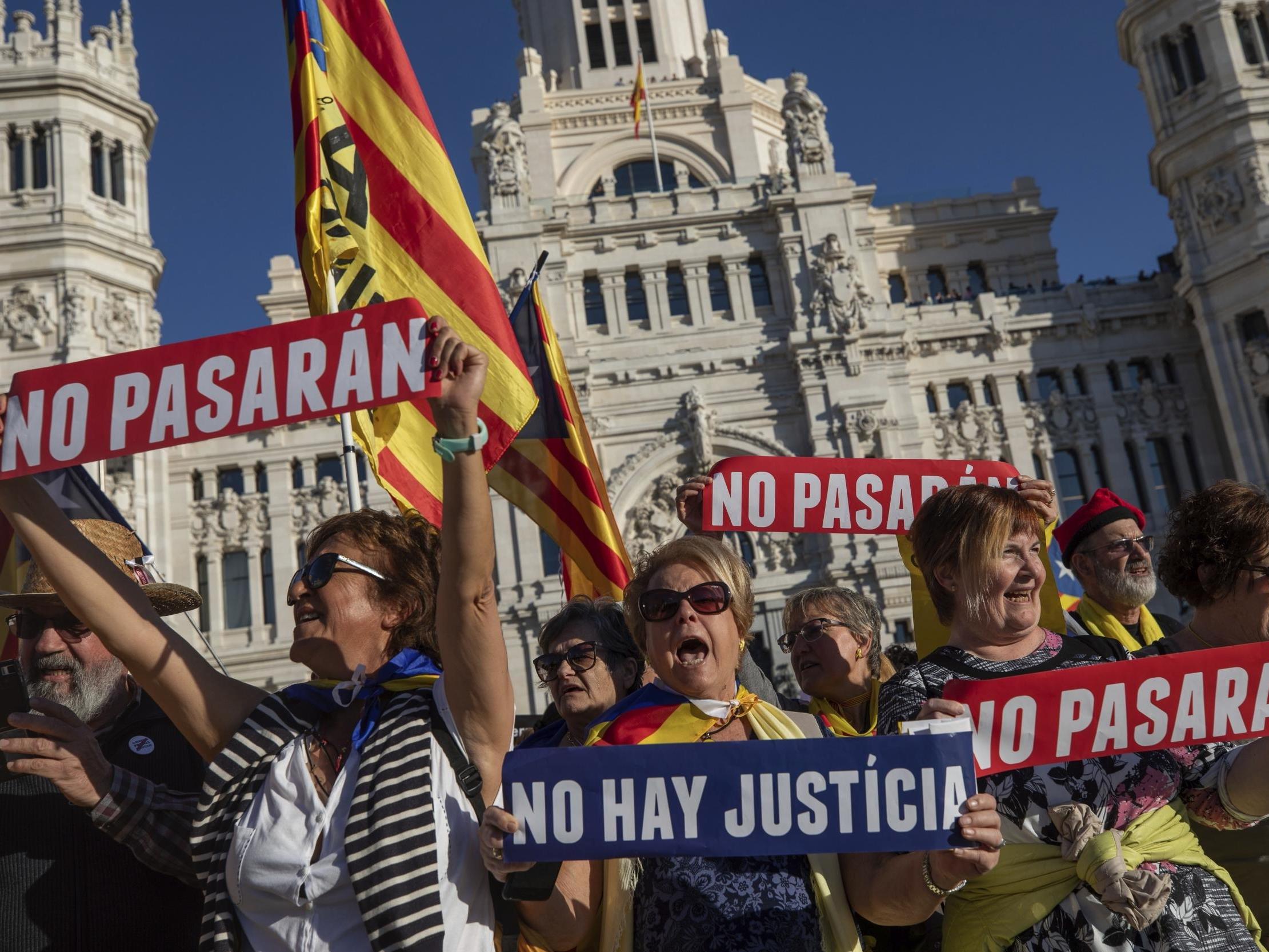 Catalan pro-independence demonstrators hold banners reading "shall not pass" and "there is no justice" during a rally in Madrid