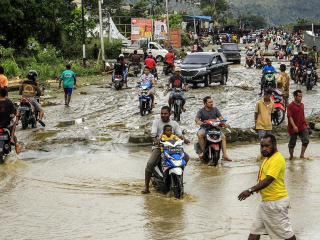 Residents ride through flood water in Sentani, near Jayapura, Papua province, Indonesia