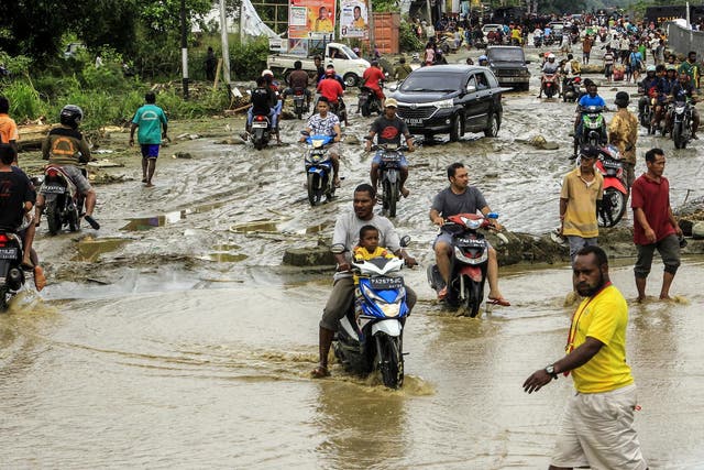 Residents ride through flood water in Sentani, near Jayapura, Papua province, Indonesia