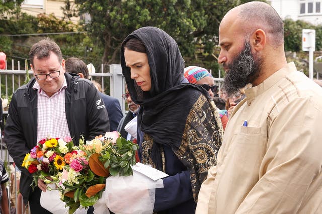 Prime minister Jacinda Ardern lays flowers while finance minister Grant Robertson looks on at the Kilbirnie Mosque