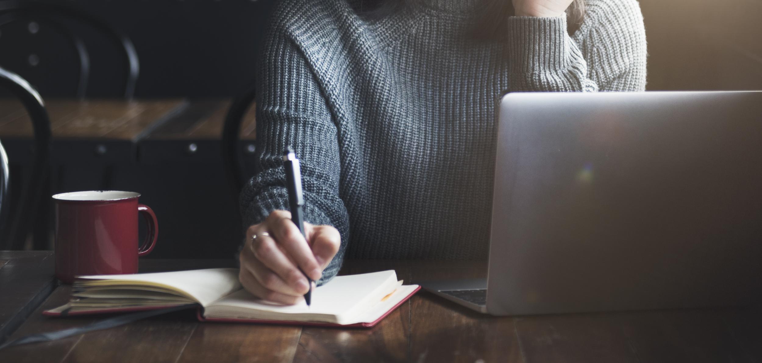 Woman writes with a coffee on table