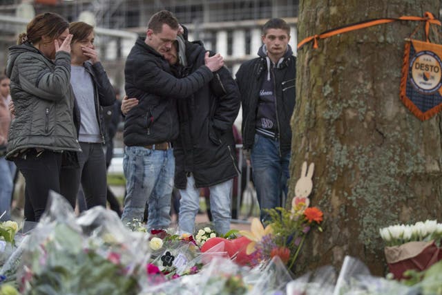 People in tears after laying flowers at a makeshift memorial for the victims of the shooting