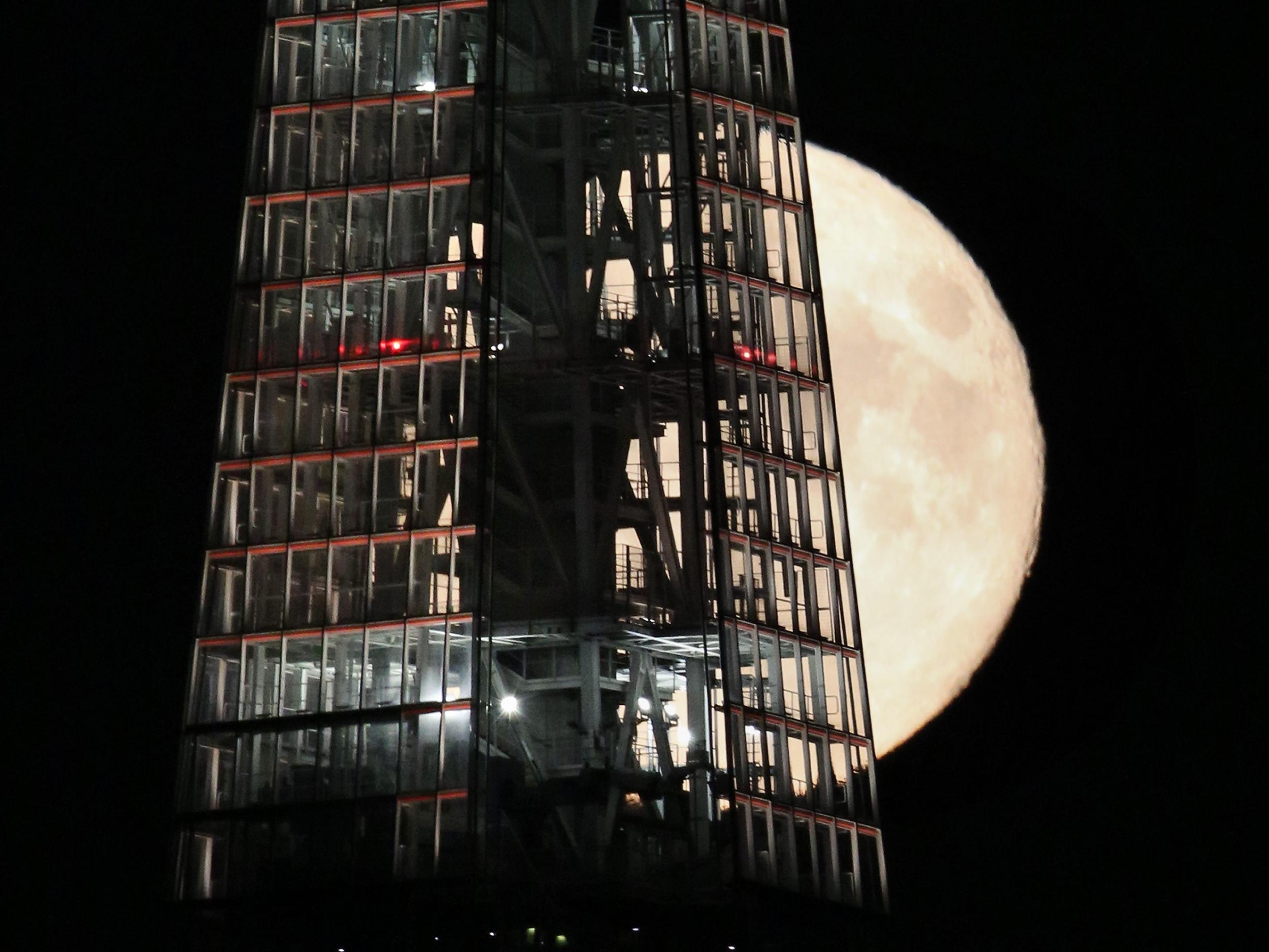 A full moon passes behind The Shard skyscraper on 9 September, 2014 in London, England