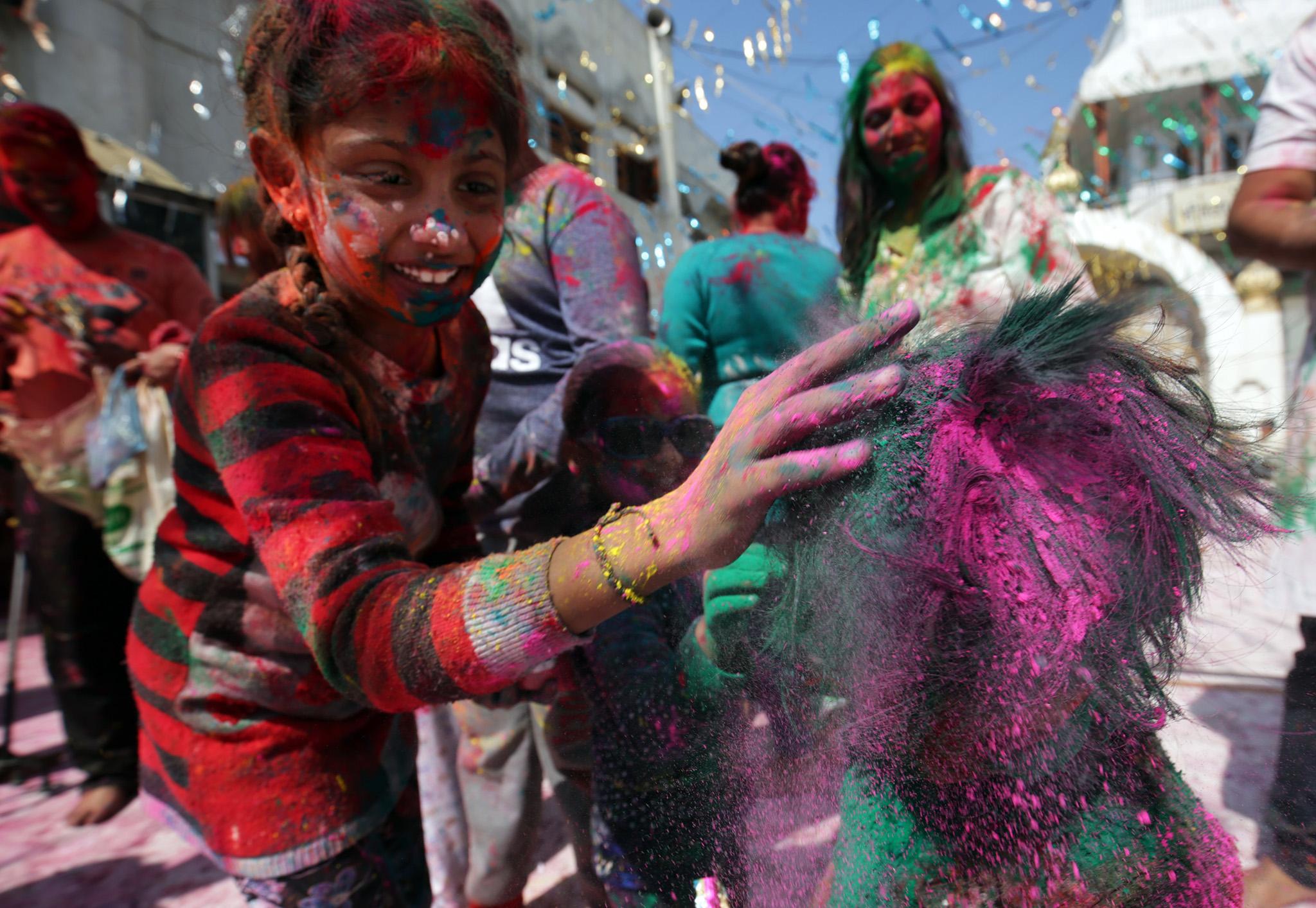 A girl smears her friend in colour during Holi festival celebrations at Durgiana Temple in Armristar, India