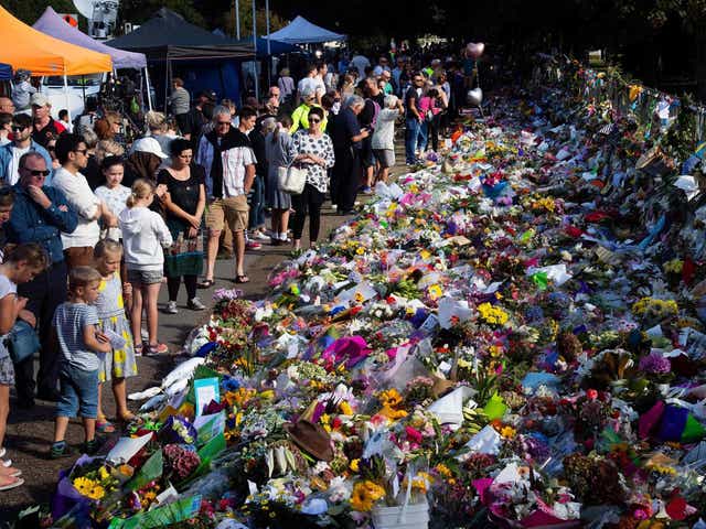 Floral tributes to those who were gunned down at the two mosques are seen against a wall bordering the Botanical Garden in Christchurch
