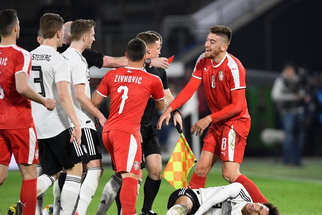 Serbia's Milan Pavkov reacts as is shown a red card by referee Bobby Madden after fouling Germany's Leroy Sane