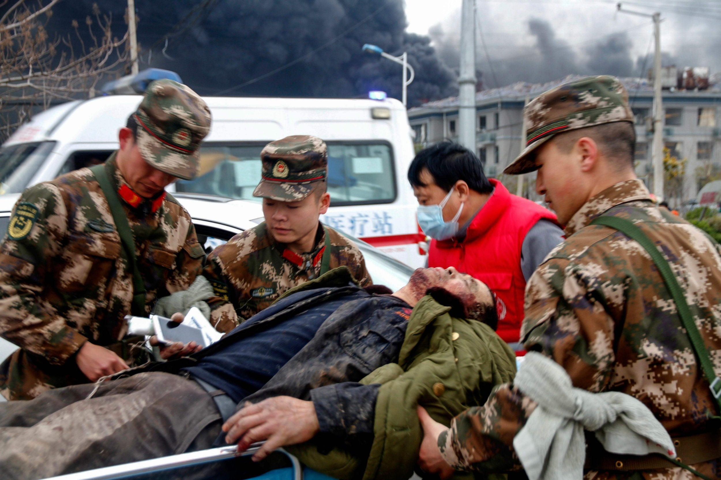 Paramilitary police officers and a medical staff transfer an injured man following factory blast