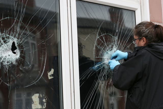 A police officer collects forensic evidence from the broken window of a mosque in Albert Road, Birmingham