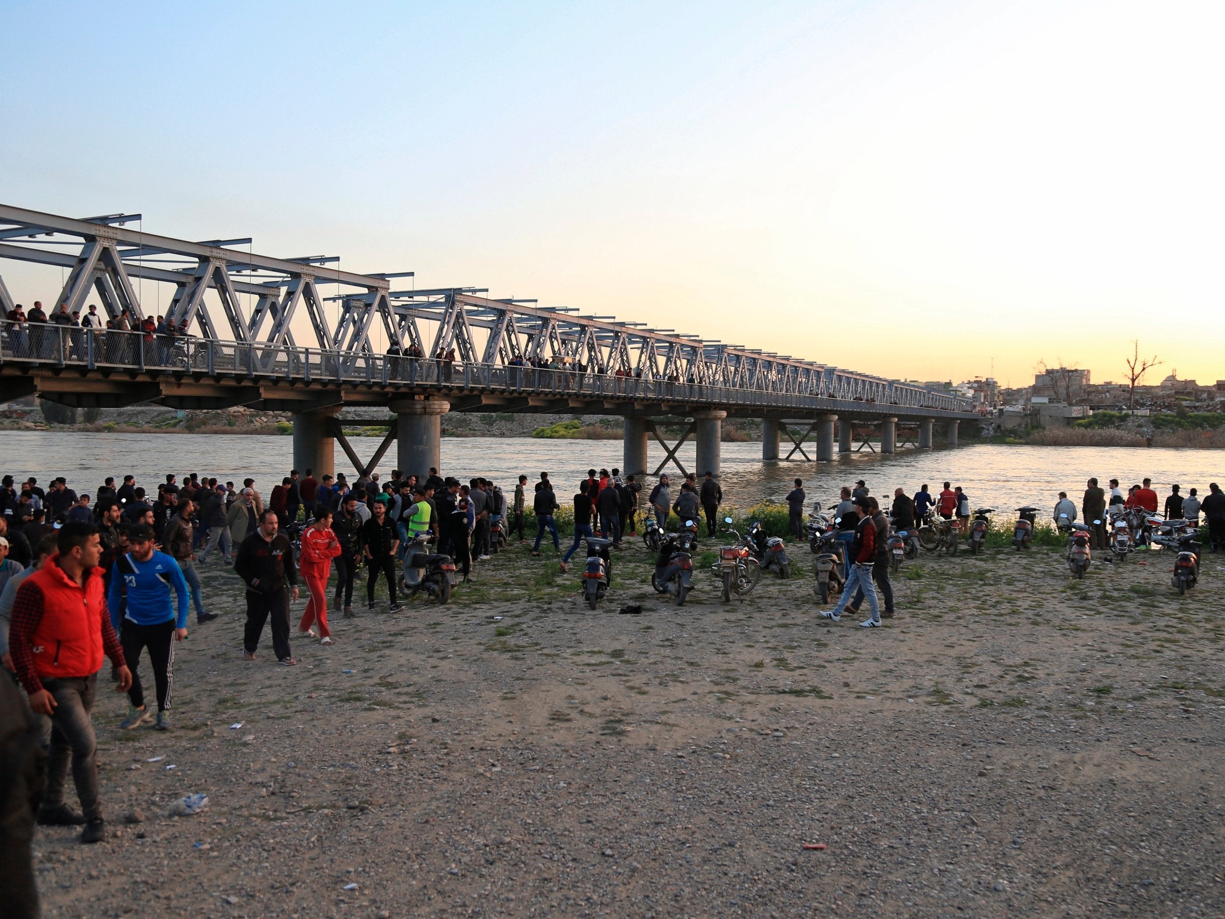 Relatives of victims wait on the bank of the Tigris where the boat sank yesterday