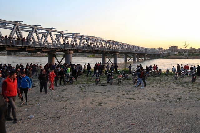 Relatives of victims wait on the bank of the Tigris where the boat sank yesterday