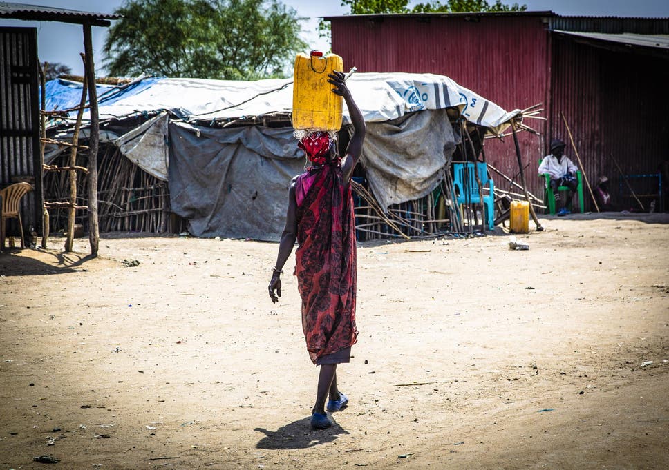 A woman walks to market carrying a jerry can of water (South Sudan)