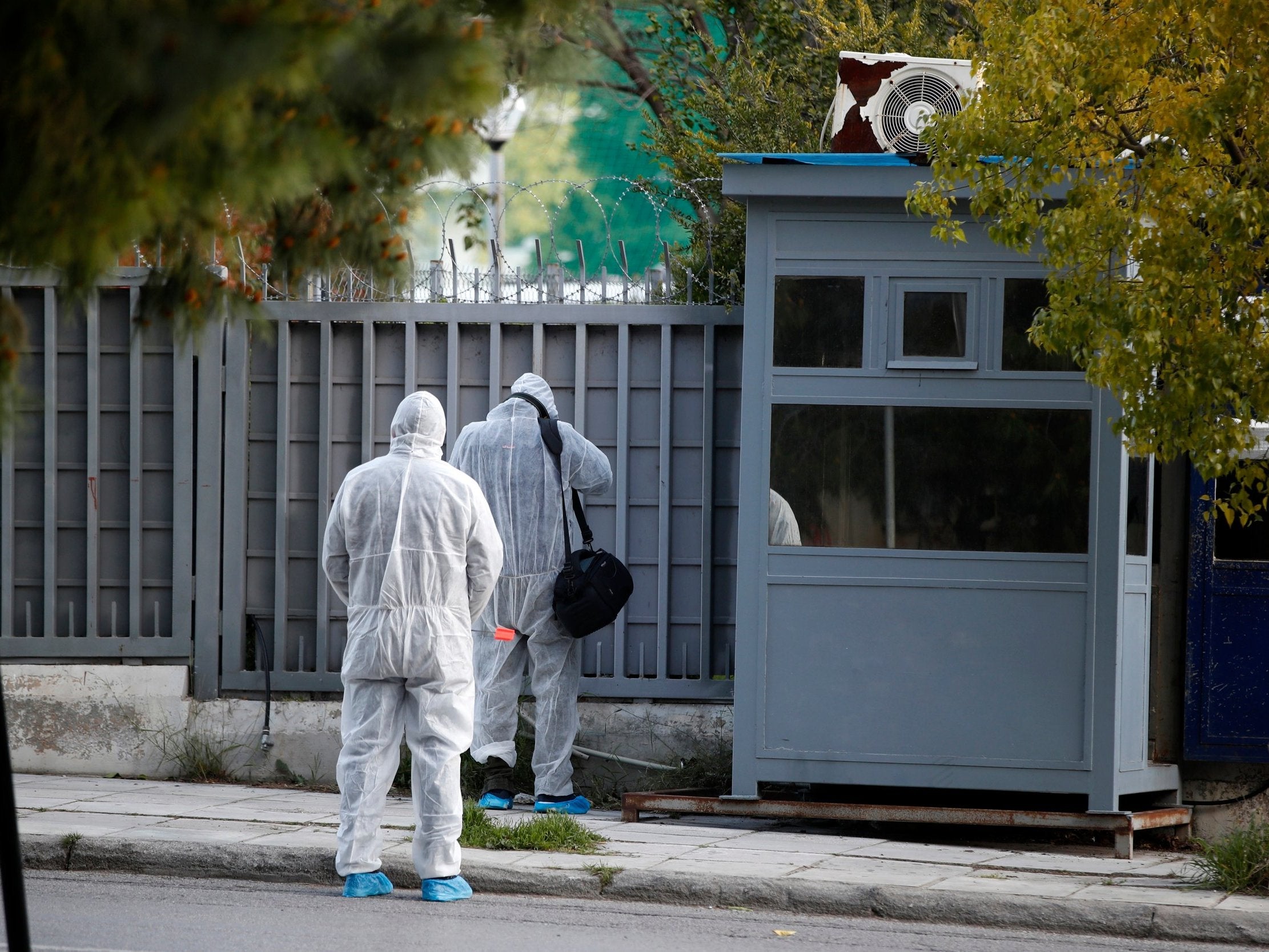 Forensic experts search the area outside the Russian consulate in Athens, Friday 22 March 2019. Police say a bomb disposal squad has been sent to the Russian consulate in Athens after cameras showed a suspicious object believed to be a hand grenade being thrown over the perimeter fence overnight.