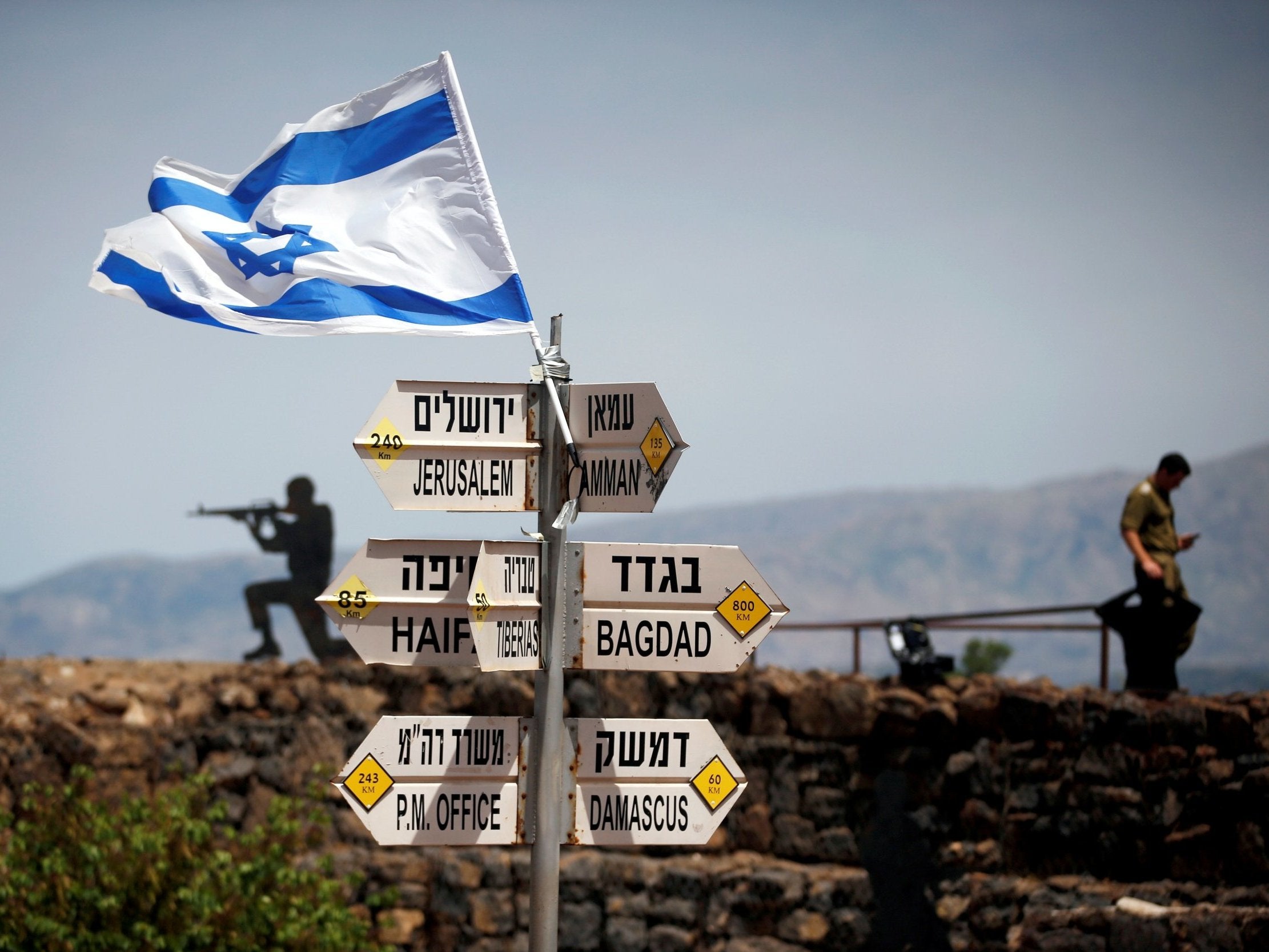 An Israeli soldier stands next to signs pointing out distances to different cities on Mount Bental, an observation post in the Israeli-occupied Golan Heights that overlooks the Syrian side of the Quneitra crossing