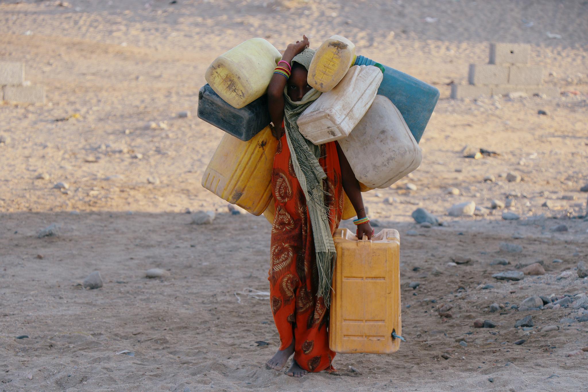 A girl carries jerry cans to fill them up with drinking water at a camp for the displaced people of Hodeidah in Yemen