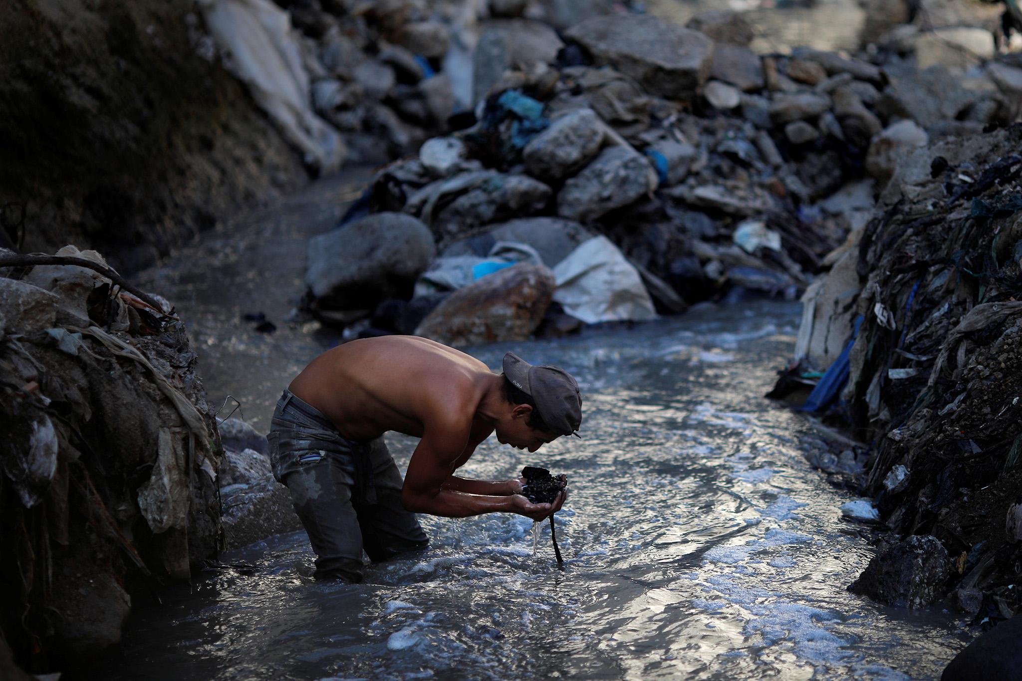 A man searches for scrap metal in contaminated sewage water in 'the Mine', an area of the largest rubbish dump of Guatemala City