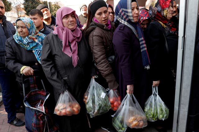 People wait in line to buy vegetables sold in a tent set up by the municipality in the Bayrampasa district of Istanbul