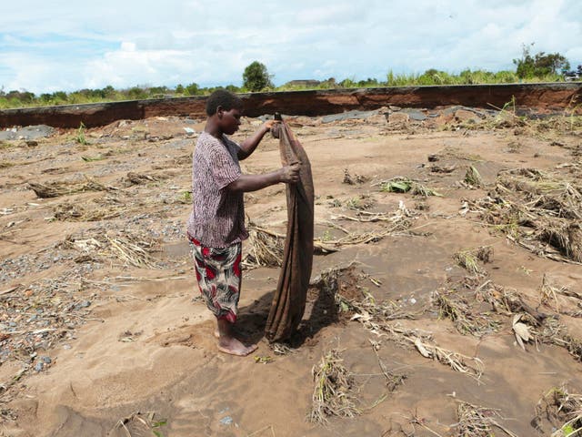 A villager salvages what remains of a piece of clothing near a section of the road damaged by Cyclone Idai in Nhamatanda about 50 kilometres from Beira, in Mozambique