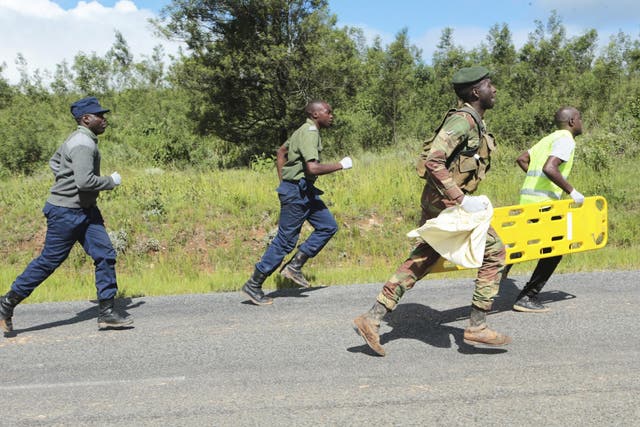 Soldiers and paramedics rush to a helicopter to carry injured survivors in Chimanimani about 600 kilometres south east of Harare, Zimbabwe, Tuesday, March, 19, 2019.