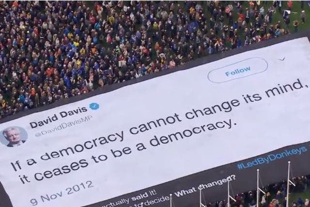 Protesters unfurl a banner featuring a David Davis quote from 2012