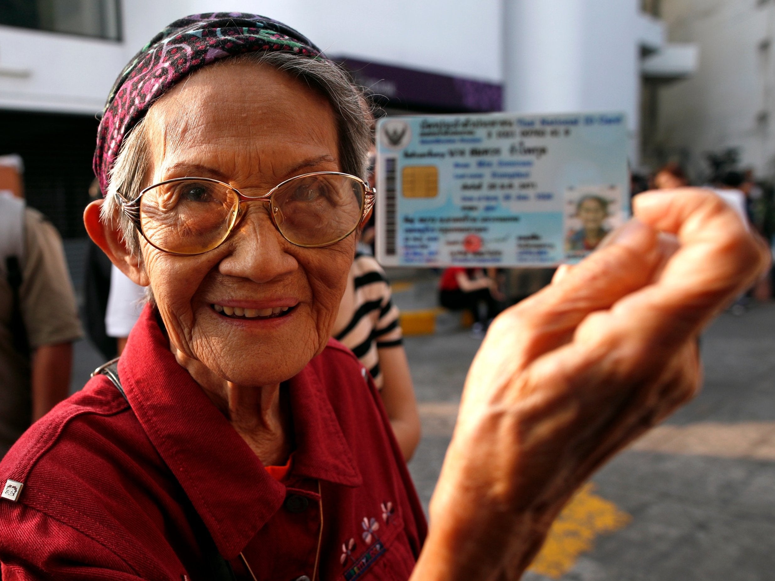 Somcuan Rumpikul, 92, shows her citizen identity card as she lines up to cast her ballot in Bangkok