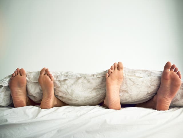 Shot of a couple’s feet poking out from under the bed sheets