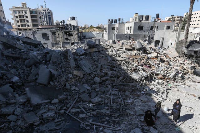 Palestinians next to rubble in Gaza City after Israeli airstrikes hit dozens of sites overnight