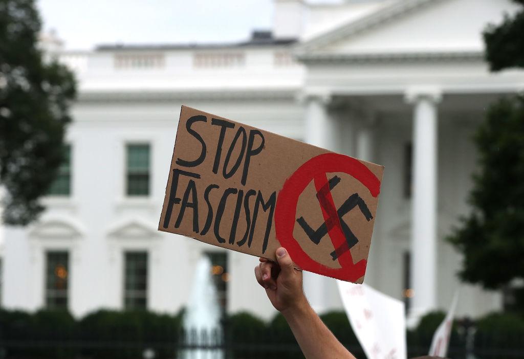 A man holds up a sign during a protest against racism gathered in front of the White House, on 14 August, 2017