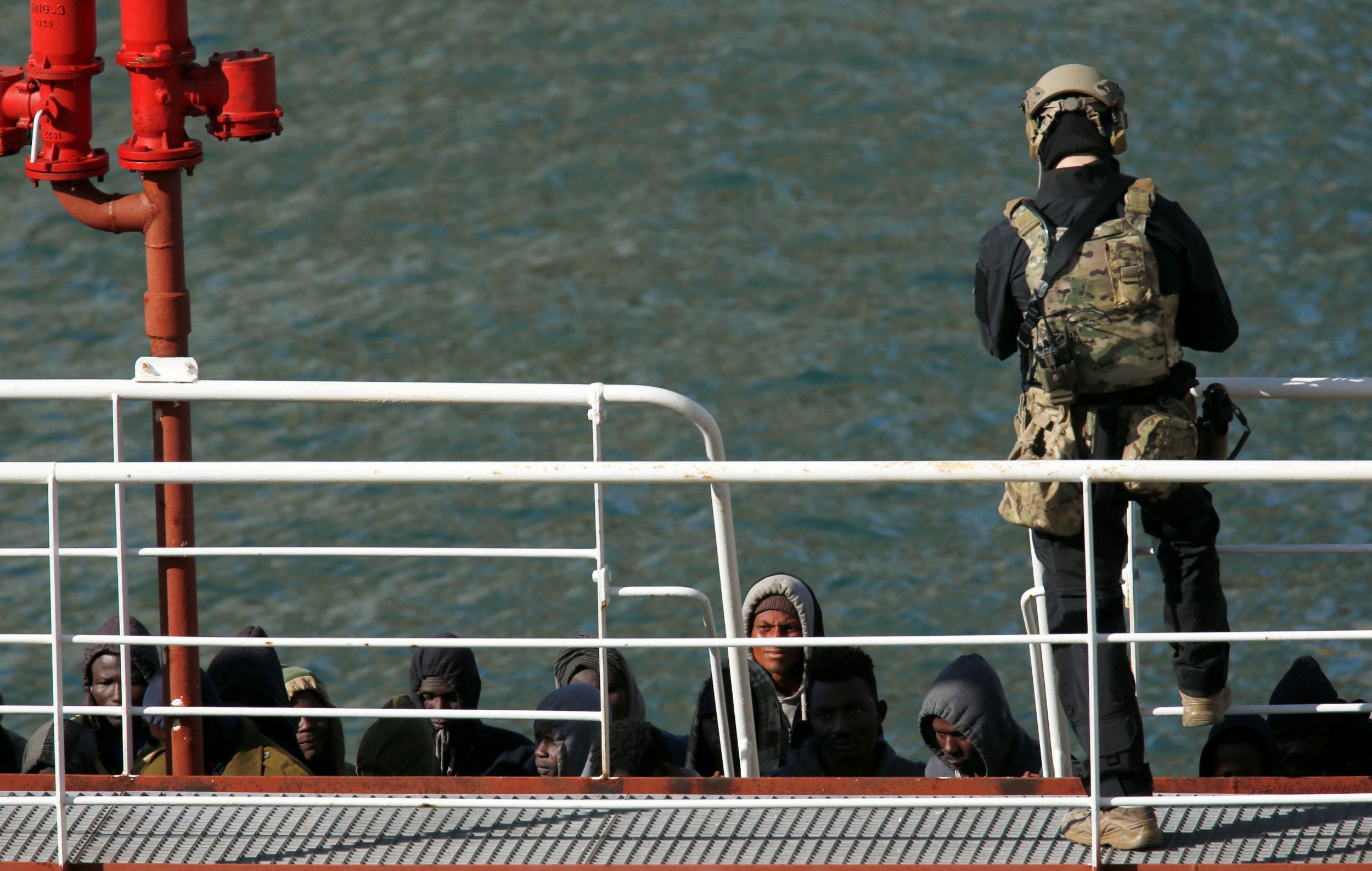 A Maltese special forces soldier guards a group of migrants on the merchant ship El Hiblu 1 after it was seized by authorities